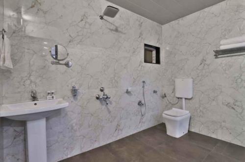 a white bathroom with a sink and a toilet at HOTEL CENTRE POINT in Mundra