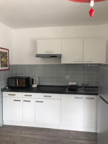 a kitchen with white cabinets and a black counter top at Apartment Hope Inn in Groß-Zimmern