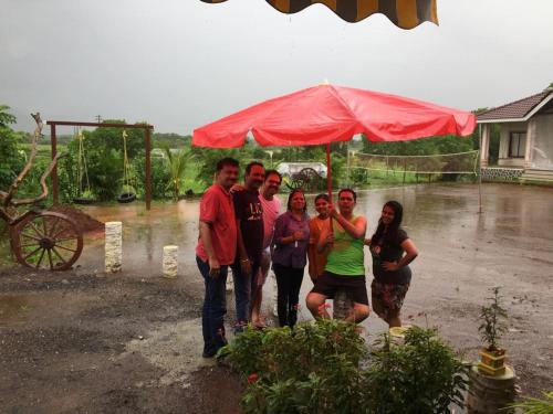 a group of people standing in the rain under a red umbrella at Windchime Cottages in Alibaug