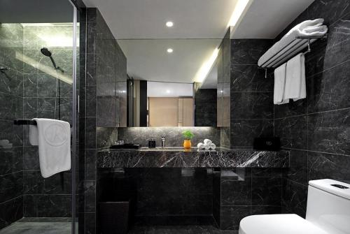 a black bathroom with a sink and a shower at 汉永瑞酒店深圳宝安机场店 in Bao'an