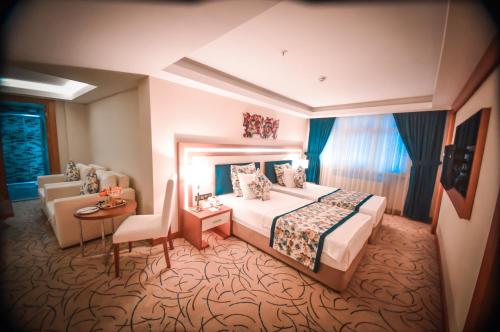 トラブゾンにあるYol Is Holiday Trabzonのベッドとシッティングエリアが備わるホテルルームです。