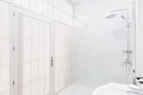baño blanco con ducha y lavamanos en Loft en primera linea del paseo marítimo, en Málaga