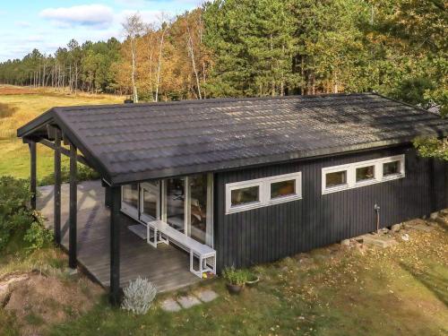 una pequeña casa negra con techo negro en 4 person holiday home in L s en Læsø
