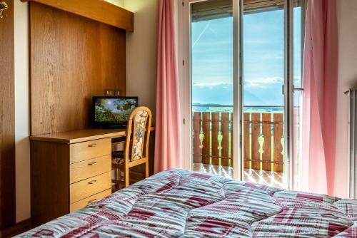 a bedroom with a bed and a desk and a window at Albergo Bucaneve in Malosco