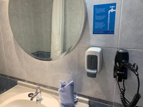 a bathroom sink with a mirror and a phone on the wall at Vistaflor Cura Marina in Playa del Cura