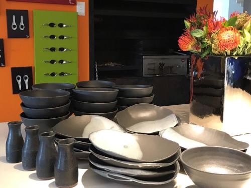 a table with plates and bowls and a vase with flowers at Bloemenzee Boutique B&B in Gordonʼs Bay