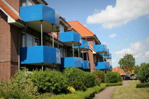 eine Reihe blauer Balkone in einem Backsteingebäude in der Unterkunft Maritime Ferienwohnung in Strandnähe in Dorum Neufeld