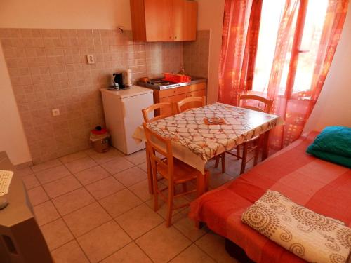 a small kitchen with a table and a room with a bed at Apartments Senny in Orebić