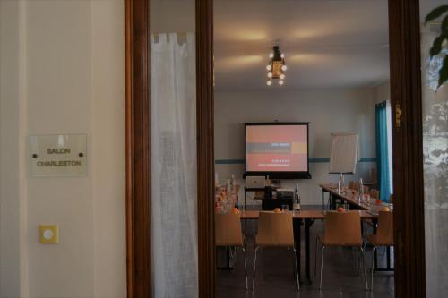 シャトライヨン・プラージュにあるLOGIS Hotel Majestic Chatelaillon Plage - La Rochelleのカンファレンスルーム(テーブル、椅子、スクリーン付)