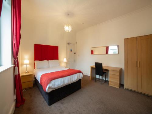 a hotel room with a bed with a desk and a red blanket at The Douglas Hotel in Hartlepool