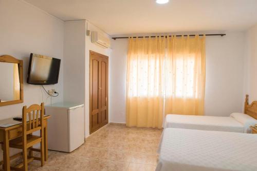 a bedroom with two beds and a desk and a television at Hotel Sierra Mar in La Unión