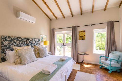 a bedroom with a large white bed and a chair at Skyview Manor in Stellenbosch