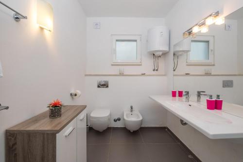 een witte badkamer met 2 wastafels en een toilet bij Villa Oceanus in Hvar