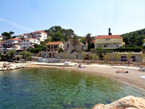 a beach with people laying on the sand and buildings at Apartments Skrivaneli in Jelsa