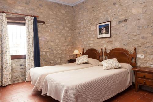 Hostal de la Rovira في Oix: غرفة نوم بسريرين ونافذة