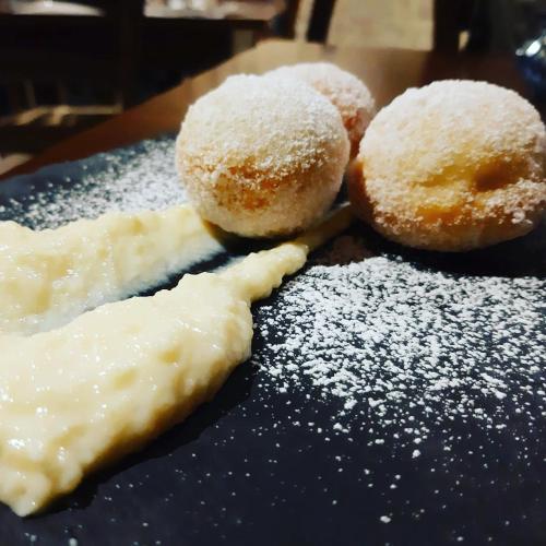 three donuts on a blue plate with powdered sugar at La Grande Quercia in Montefalco