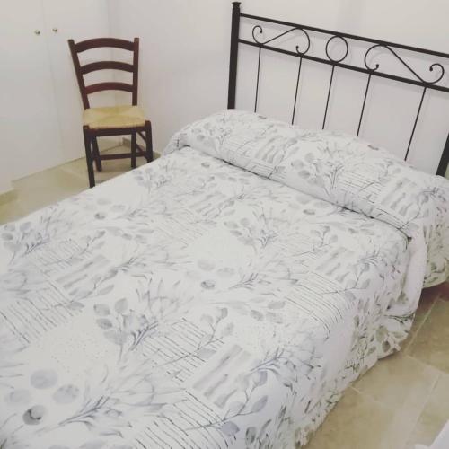 ein Bett mit einer weißen Bettdecke und einem Stuhl in der Unterkunft La Grande Quercia in Montefalco