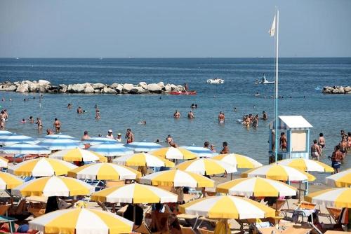 un grupo de personas en una playa con sombrillas en Hotel Oceania, en Bellaria-Igea Marina