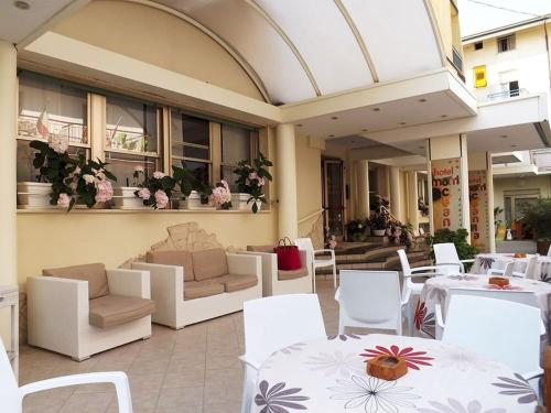un restaurante con mesas blancas y sillas blancas en Hotel Oceania, en Bellaria-Igea Marina