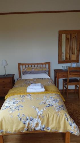 a bed with a yellow bedspread with flowers on it at Kilcreeny Lodge in Lisburn