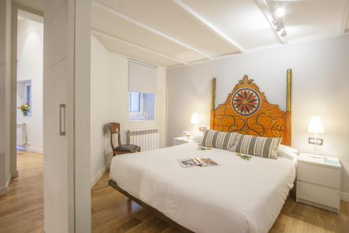 a bedroom with a large white bed with a wooden headboard at Oldtown San Sebastián Apartments in San Sebastián