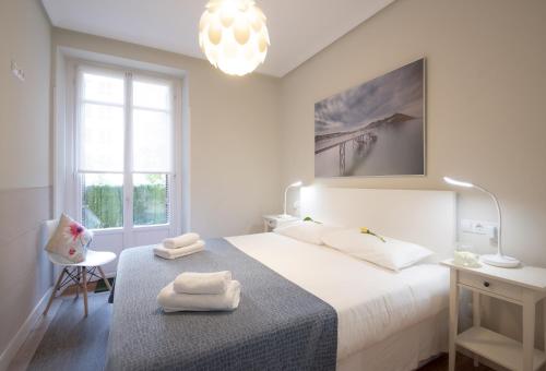 ein weißes Schlafzimmer mit einem Bett mit Handtüchern darauf in der Unterkunft Santa Clara by Oldtown Apartments in San Sebastián