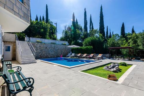 um pátio com piscina, cadeiras e árvores em Villa Oasis Cypress em Čilipi