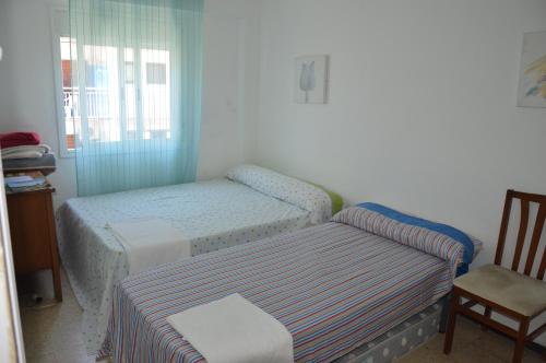 a small bedroom with two beds and a chair at Habitaciónes en apartamento in Salou