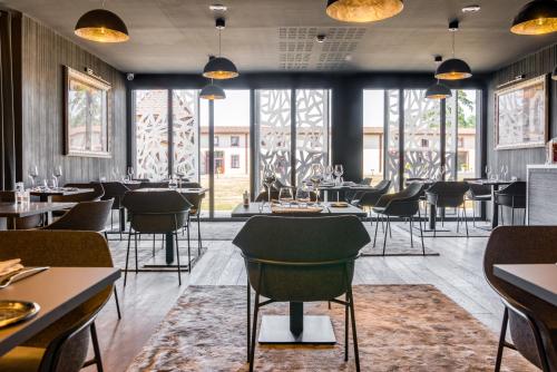 un restaurant avec des tables et des chaises et de grandes fenêtres dans l'établissement Le Domaine des Lys, à Ancenis