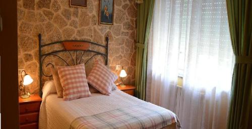 ein Schlafzimmer mit einem Bett mit zwei Kissen und einem Fenster in der Unterkunft Casa Jesús Turismo Rural in Lires