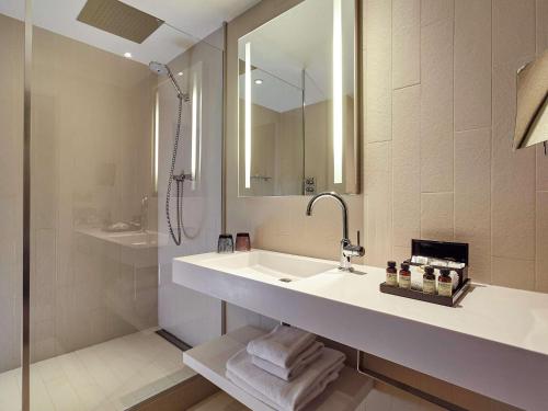
a bathroom with a tub, sink and mirror at Pullman Paris La Défense in Courbevoie
