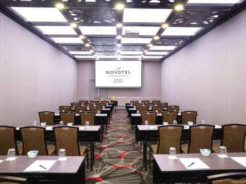 a conference room with tables and chairs and a screen at Novotel Sydney Parramatta in Sydney