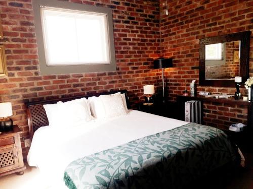 a bedroom with a white bed and a brick wall at 712@Rest in Dullstroom