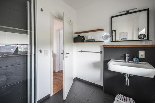 ein Bad mit einem Waschbecken und einem Spiegel in der Unterkunft Meerhuus mit Sauna in Carolinensiel