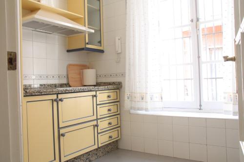 une cuisine avec des armoires jaunes et une fenêtre dans l'établissement San Lorenzo en Esencia, à Séville