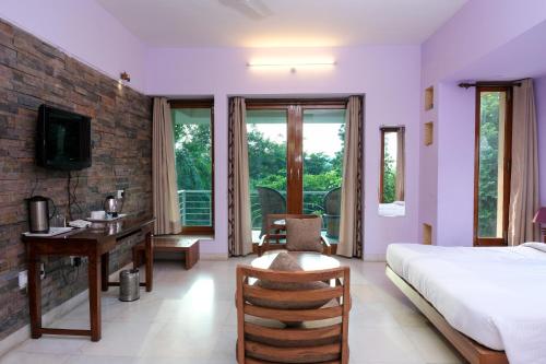 a bedroom with a bed and a desk and a television at The Chitvan Resort in Ajmer