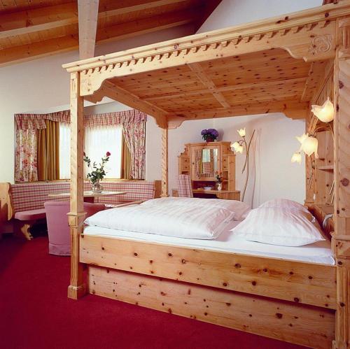 a bedroom with a wooden bed with a wooden canopy at Hotel Casa del Campo in Madonna di Campiglio
