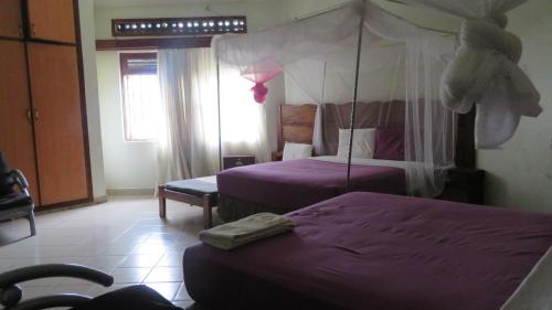 a hotel room with two beds with purple sheets at Global Village Hotel in Pakwach East