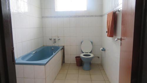 a bathroom with a blue tub and a toilet at Global Village Hotel in Pakwach East