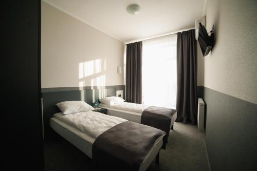 two beds in a hotel room with a window at GOLDEN RING in Ternopilʼ