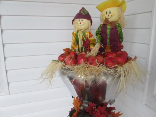 two dolls sitting on top of a bowl of apples at Gîte Les Acres Tranquilles B&B in Port-Daniel