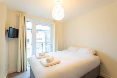 een slaapkamer met een wit bed en handdoeken bij Amazing Modern 2 Bedroom Flat in Greenwich for 4 people in Londen