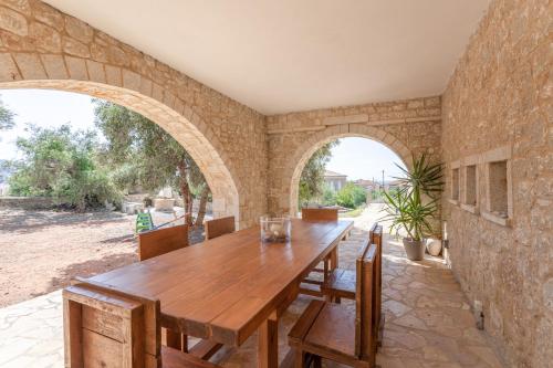 a dining room with a wooden table and two arches at Orion Residence Mani in Agios Nikolaos