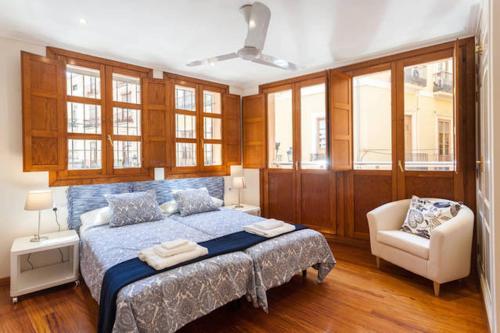 um quarto com uma cama, uma cadeira e janelas em Apartamento Torres em Valência