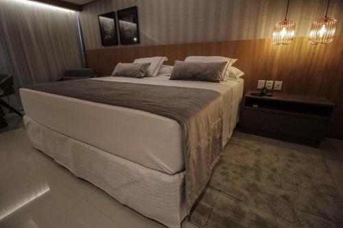 a bedroom with a large white bed with a night stand at Oscar Hotel Executive in Porto Velho