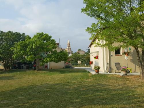 a yard with a house and a church in the background at Gite Pourquoi Pas in Montégut-Lauragais