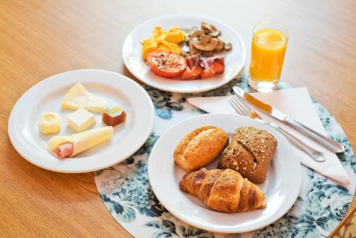 two plates of breakfast food on a wooden table at Lam Hotel Convento do Desagravo in Oliveira do Hospital