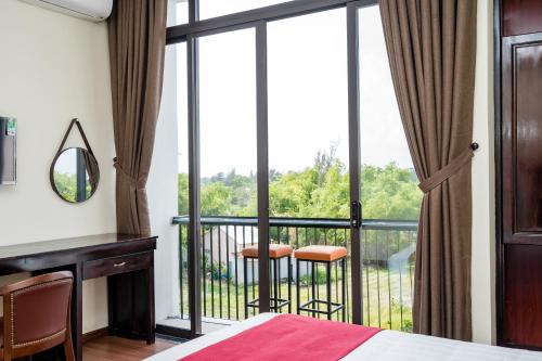 a bedroom with a bed and a balcony with a view at Ancient River Villa in Hoi An
