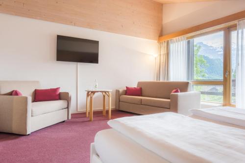 レンクにあるHotel Kreuz Lenkのベッド、ソファ、テレビが備わるホテルルームです。