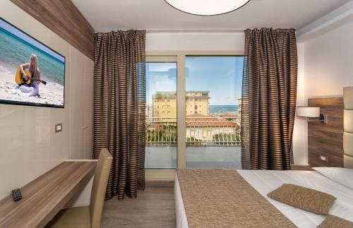 a bedroom with a bed and a large window at Hotel Pineta Mare in Lido di Camaiore